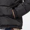 Close-up of a person's hand in the pocket of a black puffer jacket. Voir les images du produit