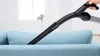 A hand is using a vacuum cleaner attachment to clean the crevice of a light blue sofa. Produktbild-Vorschau