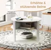 A white round coffee table with a shelf, placed on a patterned rug in a living room setting. A robot vacuum cleaner is visible underneath the table. Produktbild-Vorschau