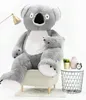 A large plush koala bear sitting on a chair, with a small side table next to it. Náhľad obrázku produktu
