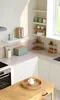 A well-lit kitchen scene with various kitchenware items displayed on countertops and shelves. Produktbild-Vorschau