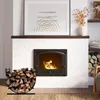 A fireplace with a wood rack in front, filled with firewood. A framed artwork hangs above the fireplace. Produktbild-Vorschau
