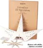 A white paper star lantern with LED lights and its battery pack are displayed in front of its packaging. Podgląd zdjęcia produktu