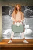 A woman is posing with a handbag in front of a black and white mural. Voir les images du produit