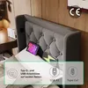 Close-up of a bed headboard with integrated charging ports and devices on the bed. Náhled obrázku produktu