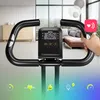 Close-up of the handlebars and display of a stationary exercise bike, with a blurred background of a living room and icons representing fitness metrics. Anteprima dell’immagine prodotto
