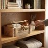 A wooden box filled with rolled towels and a wallet, placed on a wooden shelf. Náhľad obrázku produktu