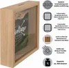 A wooden money box with a glass front displaying a picture with the text 'Adventure Waits'. The image also includes informational graphics and text about the product's features and dimensions. Produktbild-Vorschau