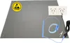 An anti-static ESD computer mat with accessories, including a wrist strap and grounding cable, is laid out on a white background. A power strip with two outlets is also visible. Produktbild-Vorschau