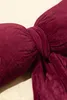 A close-up of a burgundy velvet bow-shaped pillow. Produktbild-Vorschau