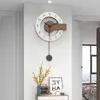 A modern living room with a decorative wall clock, a vase of flowers, and a framed picture on a shelf. Produktbild-Vorschau