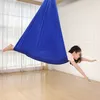 A young girl is swinging in a blue hammock indoors. Produktbild-Vorschau