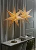 Two star-shaped lamps are placed on a marble-top console table, with curtains in the background and pinecones and greenery as decoration. Podgląd zdjęcia produktu