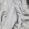 Nahaufnahme einer hellgrauen Fleecedecke, die ihre weiche, plüschige Textur mit Falten und Schatten zeigt Produktbild-Vorschau