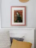 A framed picture of a canyon hangs on a wall above a bed with pillows. Produktbild-Vorschau