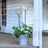 Two LED decorative spheres on stakes are placed in a galvanized bucket filled with white and purple flowers on a wooden porch. Produktbild-Vorschau