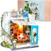 A miniature dollhouse model of a loft apartment, complete with furniture, plants, and decorative elements, displayed on a white background with its packaging in the upper right corner. Anteprima dell’immagine prodotto