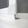 A close-up view of the bottom corner of a white shower enclosure or bathtub screen, showing its base and a section of the wall. Produktbild-Vorschau