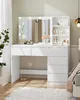 A white vanity table with a lighted mirror and drawers, set up in a bedroom. Voir les images du produit