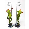 Two decorative frog figurines are shown standing under a shower. Produktbild-Vorschau