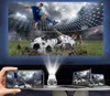 A projector displaying a soccer game on a large screen, with various devices like a smartphone, laptop, and tablet also showing the game, all connected to the projector. Produktbild-Vorschau