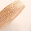 A close-up view of a round, woven straw cushion on a light-colored wooden floor. Produktbild-Vorschau