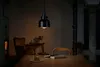 A dimly lit dining room with a pendant light hanging over a wooden table. Produktbild-Vorschau
