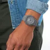 A person wearing a grey G-Shock watch on their wrist, with a denim shirt visible. Náhled obrázku produktu