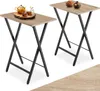 Two folding side tables with wooden tops and black metal frames are shown against a white background. One table has a teapot and two cups on it, while the other has two decorative bowls. Produktbild-Vorschau