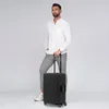 A man stands holding a black trolley suitcase. Podgląd zdjęcia produktu