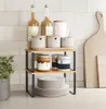 A two-tier kitchen shelf holding various kitchen items like bottles, jars, and plates, placed on a countertop against a tiled wall. Produktbild-Vorschau