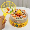 A hand holding a yellow net with toy ducks inside, with a duck-themed game in the background. Náhľad obrázku produktu
