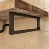 A close-up view of a black metal shelf bracket supporting a wooden shelf, mounted on a tiled wall. Produktbild-Vorschau