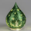 A green glass teardrop-shaped decorative light with a frosted winter scene. Produktbild-Vorschau