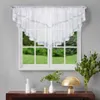 A white scalloped valance curtain with decorative trim is hung over a window with a view of a green lawn and trees. Below the window, a dark wooden console table displays decorative items including vases, a lamp, and greenery. Podgląd zdjęcia produktu