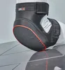 A close-up of a black knee protector with red trim, placed on a reflective surface. Anteprima dell’immagine prodotto
