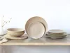 A set of stoneware plates and bowls with a textured design, arranged on a wooden shelf against a white background. Náhľad obrázku produktu