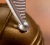 A close-up shot of a golden object with a silver metallic detail attached. Podgląd zdjęcia produktu