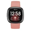 A Fitbit Versa 4 smartwatch with a pink band is shown against a white background. Produktbild-Vorschau