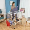 A woman is hanging laundry on a multi-tiered drying rack in a room. Náhled obrázku produktu