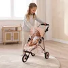 A young girl is playing with a doll in a stroller in a room. Náhľad obrázku produktu