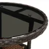 Close-up of the edge of a round table with a glass top and woven rattan base. Náhled obrázku produktu