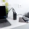A black power bank is charging a laptop, a tablet, and a smartphone on a white desk. Anteprima dell’immagine prodotto