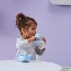 A young child drinking from a bottle while sitting at a table. Náhled obrázku produktu