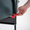 A hand is shown operating a red latch on a dark green object, which appears to be part of a larger item. Produktbild-Vorschau