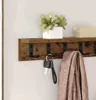 A wooden shelf with hooks mounted on a wall, holding keys and a scarf. There are also decorative plants and a box on the shelf. Podgląd zdjęcia produktu