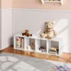 A white cube shelf unit filled with toys and blankets, placed against a white paneled wall in a child's room. Produktbild-Vorschau