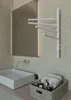 A modern bathroom sink area with a white rectangular sink, a chrome faucet, a large illuminated mirror, and a white electric towel warmer with four rotating arms mounted on a textured wall. A woven basket containing toiletries and towels is placed on the c Podgląd zdjęcia produktu