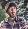 A man wearing a beanie and flannel shirt outdoors. Náhled obrázku produktu