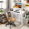 A modern home office setup featuring a white standing desk with a computer, laptop, and accessories, next to a window and a side table. Anteprima dell’immagine prodotto